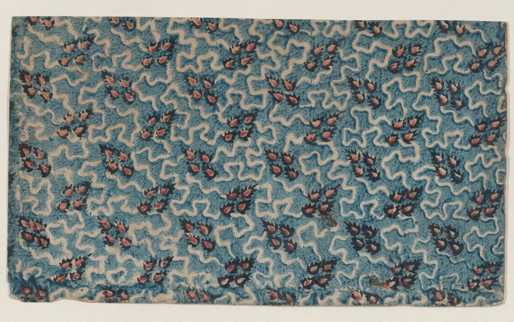 Sheet of paper with a blue and white wavy pattern scattered with small red sprigs