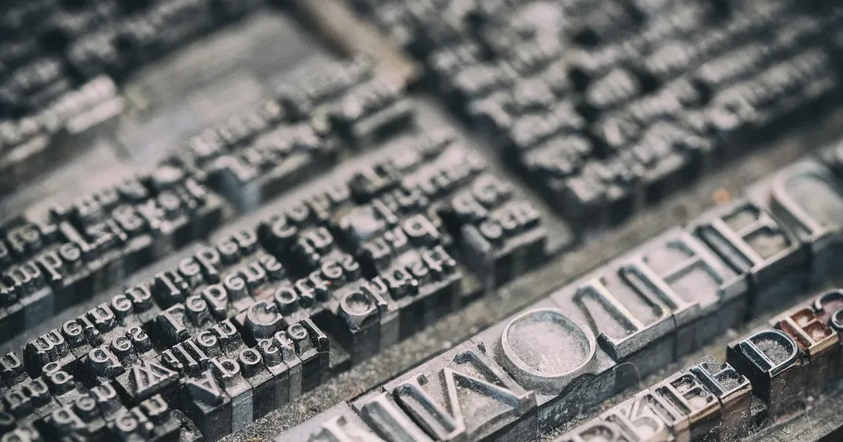 Close view of worn metal type set in lines, the letters reversed