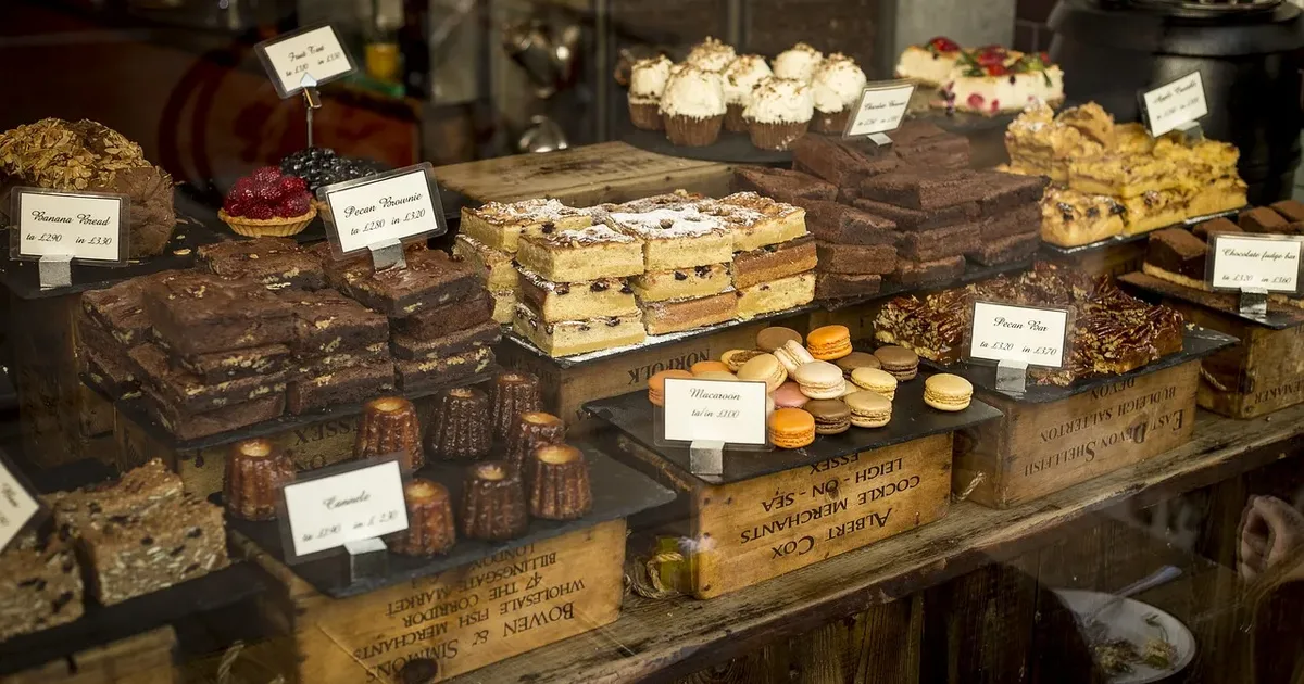 Café counter of brownies, cakes, macarons and canelés with handwritten price cards
