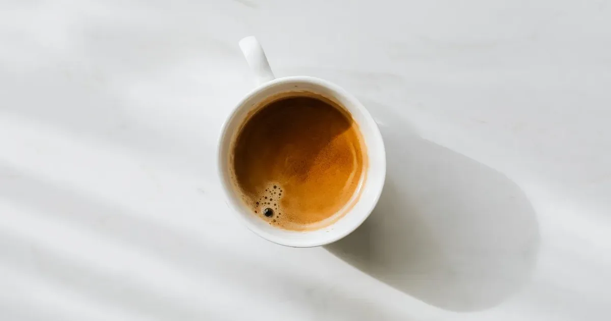 Cup of espresso from above on a white table in soft shadow