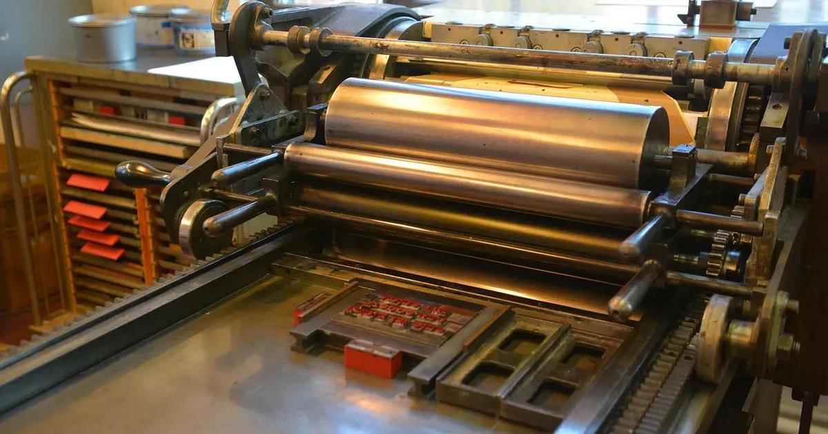 Letterpress proofing press with inked rollers over a bed of locked-up type